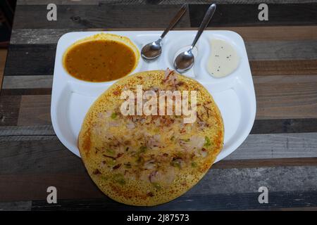 L'Uttapam est servi avec du chutney sur une assiette blanche, un plat de légumes indiens. Banque D'Images