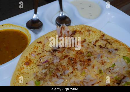 L'Uttapam est servi avec du chutney sur une assiette blanche, un plat de légumes indiens. Banque D'Images