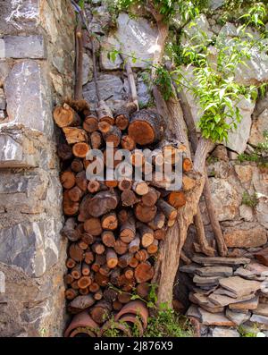 Pile de bois de chauffage dans un jardin à côté de la pierre. Vertical et gros plan. Banque D'Images