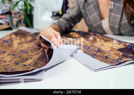 Portrait d'une couturière dans une veste à carreaux travaillant dans son atelier de couture, elle montrant l'intérieur de la doublure de vêtements Banque D'Images