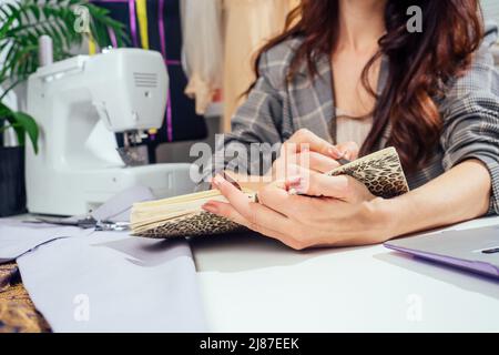 une jolie couturière aux cheveux longs écrit dans un carnet. la tailleur crée une collection de tenues. jeune femme designer vêtements note des idées Banque D'Images