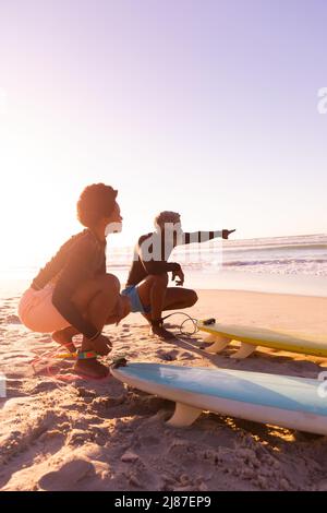 Homme afro-américain senior pointant vers la mer tout en appréciant avec une femme mûre à la plage Banque D'Images