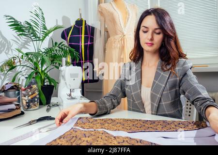 Portrait d'une couturière dans une veste à carreaux travaillant dans son atelier de couture, elle montrant l'intérieur de la doublure de vêtements Banque D'Images