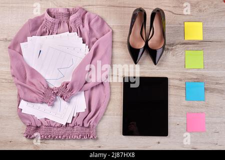 Haut de la page chemisier rose couché plat avec papiers de travail et chaussures. Tablette avec notes adhésives sur le bureau. Banque D'Images