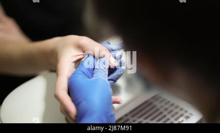 Gros plan des mains du manucuriste à l'aide d'un dissolvant électrique pour cuticules à ongles Banque D'Images