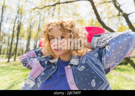 Jolie jeune fille caucasienne tenant une planche à roulettes dans le parc de taille moyenne à l'extérieur . Photo de haute qualité Banque D'Images