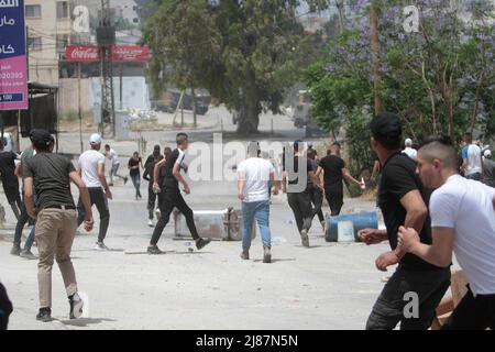 Djénine, Palestine. 13th mai 2022. Les Palestiniens jettent des pierres sur les forces israéliennes lors d'une opération militaire dans le camp de réfugiés de Djénine, près de la ville de Djénine, en Cisjordanie occupée. Des affrontements ont éclaté entre des hommes armés palestiniens et les forces israéliennes dans la région. Crédit : SOPA Images Limited/Alamy Live News Banque D'Images