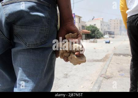 Djénine, Palestine. 14th mai 2022. Les Palestiniens détiennent des pierres lors d'une opération militaire menée par les forces israéliennes dans le camp de réfugiés de Jénine, près de la ville de Jénine, en Cisjordanie occupée. Des affrontements ont éclaté entre des hommes armés palestiniens et les forces israéliennes dans la région. Crédit : SOPA Images Limited/Alamy Live News Banque D'Images