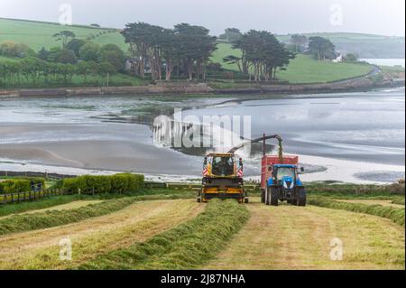 Rathclaran, West Cork, Irlande. 13th mai 2022. Alors que le soleil se couche et que la lune se lève, Patrick O'Donovan, un entrepreneur basé à West Cork, utilise une moissonneuse New Holland FR550 pour collecter de l'ensilage pour le producteur laitier Declan O'Donovan dans sa ferme près de Rathclaran, West Cork. Declan laitait 100 vaches et espère que 3 coupes d'ensilage seront effectuées cette année. Crédit : AG News/Alay Live News Banque D'Images