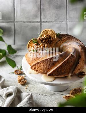Gâteau Bundt dans la composition décoré avec des noix d'orange et de glaçage. Fond de mosaïque gris Banque D'Images