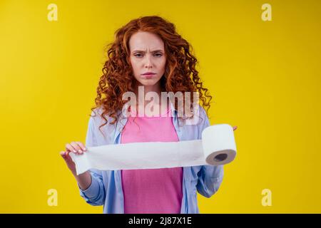 Magnifique rouge curly Ginger femme tenant papier toilette rouleau sur fond jaune Banque D'Images