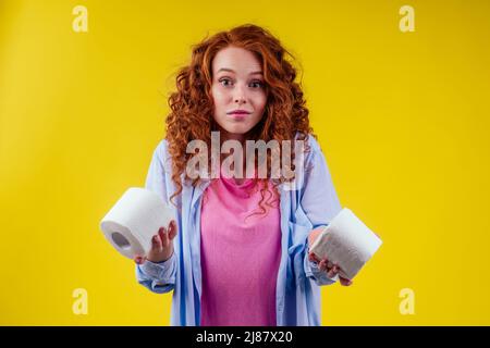 Magnifique rouge curly Ginger femme tenant papier toilette rouleau sur fond jaune Banque D'Images