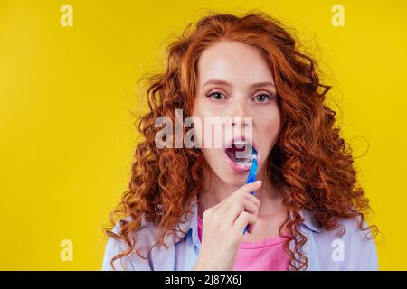 femme gingembre rougeâtre avec brosse à dents écologique et dentifrice sur fond jaune studio Banque D'Images