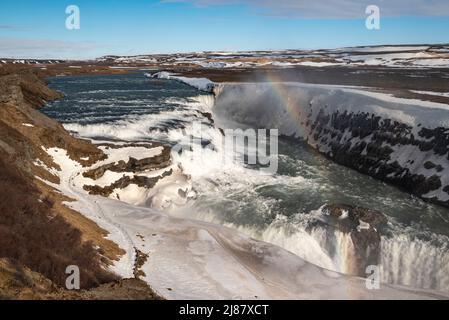 Vue panoramique sur les étages supérieurs de la puissante cascade de Gullfoss en hiver, avec un bel arc-en-ciel petit, Golden Circle route, Islande Banque D'Images