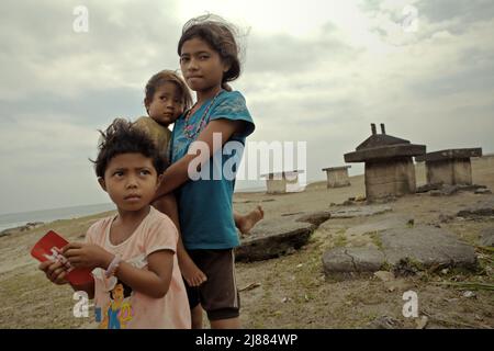 Enfants d'âge scolaire prenant soin d'un bébé dans le village de Ratenggaro, île de Sumba, province de Nusa Tenggara est, Indonésie. © Reynold Sumayku Banque D'Images