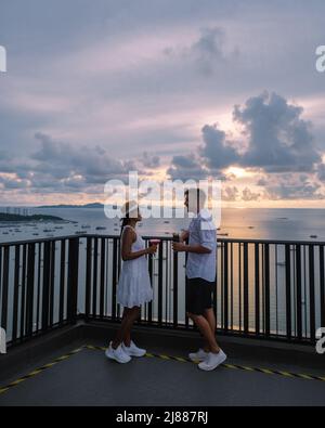 Vue depuis la terrasse du Hilton Sky Bar au coucher du soleil. Pattaya bar sur le toit Thaïlande, un couple homme, et des femmes regardant le coucher du soleil depuis un bar sur le toit Banque D'Images