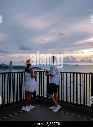 Vue depuis la terrasse du Hilton Sky Bar au coucher du soleil. Pattaya bar sur le toit Thaïlande, un couple homme, et des femmes regardant le coucher du soleil depuis un bar sur le toit Banque D'Images