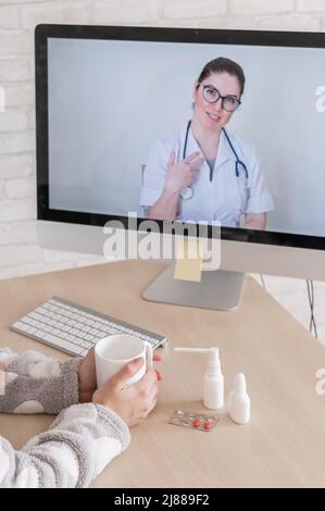 Une femme atteinte d'une maladie respiratoire est en congé de maladie et regarde un médecin consultant en vidéo informatique. Le thérapeute fournit une couverture en direct pour Banque D'Images