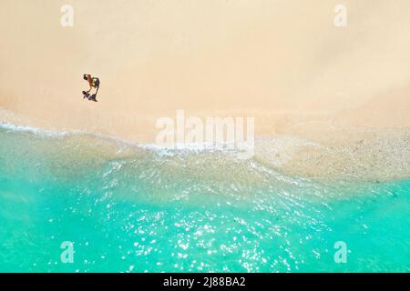Un couple marche le long de la plage de l'île Maurice dans l'océan Indien. Vue de dessus de la plage avec l'eau turquoise sur l'île tropicale de Maurice.Aerial Banque D'Images