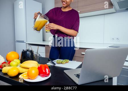 latino femme travaillant à la barre de jus et de couper des fruits, de faire des smoothies frais à partir de bananes, d'orange et de melon. elle utilise des tubes réutilisables en métal écologique et Banque D'Images