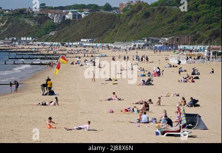 Les gens apprécient le temps chaud sur la plage de Bournemouth à Dorset. Les températures s'échauffent pour le week-end, car la plupart des Britanniques peuvent s'attendre à être baignés de soleil. Cependant, le Bureau met a averti qu'un samedi ensoleillé, qui serait idéal pour un barbecue, pourrait être suivi par de fortes pluies et des orages. Date de la photo: Samedi 14 mai 2022. Banque D'Images