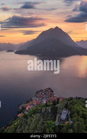 Vue panoramique verticale sur le château de Vezio avec le village de Varenna et les montagnes en arrière-plan pendant le coucher du soleil d'été. Tir de drone dans le lac de Côme. Varenna Banque D'Images