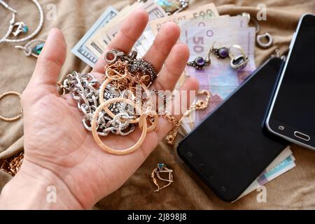 Maraudeurs main avec un tas de bijoux volés, de l'argent et des smartphones sur tissu militaire uniforme. Pillage par des soldats russes dans le citi ukrainien Banque D'Images