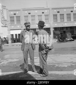 Calipatria, Vallée impériale. Les cueilleurs de pois inactifs discutent des perspectives de travail. Californie. [Panneaux : « Hotel - Coffee Shop - cocktails »]. Banque D'Images