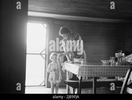 Femme et enfant de la caisseuse de tabac. La fille la plus littles vient de l'extérieur pour manger quelque chose pendant que la mère fait ses travaux ménagers. L'enfant à côté du bébé est appelé dans ce pays le "bébé genou". Comté de Person, Caroline du Nord. Banque D'Images