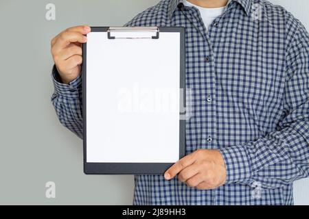 Homme tenant la presse-papiers avec une feuille de papier blanche vierge Banque D'Images