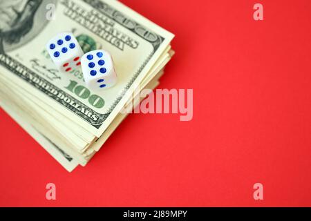 Concept d'argent, de finance et de jeu. Gros plan sur une centaine de billets américains et deux dés blancs en haut montrant les chiffres six et six Banque D'Images
