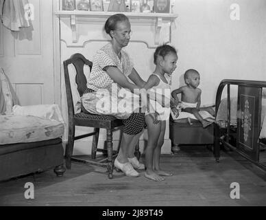 Washington, D.C. Mme Ella Watson, charfemme du gouvernement qui habille ses petits-enfants. Banque D'Images