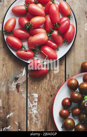 Tomates cerises rouges et noires sur fond de bois. Banque D'Images