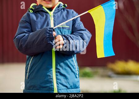 Un petit garçon patriotique porte le drapeau ukrainien. Tenez-vous avec l'Ukraine. Soutenir l'Ukraine. Arrêter le concept d'agression russe. Arrêter la guerre en Ukraine. Priez pour l'Ukraine Banque D'Images