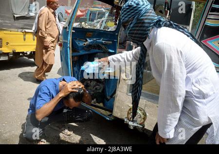 Les navetteurs sont arroser sur sa tête et le visage pour battre la chaleur du soleil brûlant pendant la journée chaude de l'été, au bord de la route situé sur la région de Halanaka de Hyderabad le samedi 14 mai 2022. Banque D'Images