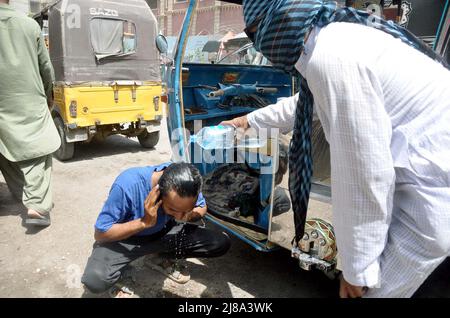 Les navetteurs sont arroser sur sa tête et le visage pour battre la chaleur du soleil brûlant pendant la journée chaude de l'été, au bord de la route situé sur la région de Halanaka de Hyderabad le samedi 14 mai 2022. Banque D'Images