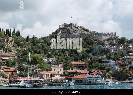 Le village de Kaleköy à flanc de colline avec son château médiéval Banque D'Images