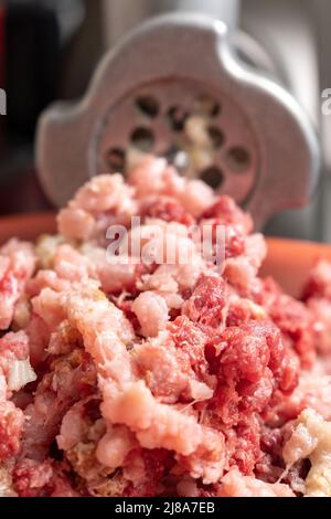 Le moulin à viande et la viande hachée tombent. Mise au point sélective. Photo verticale Banque D'Images