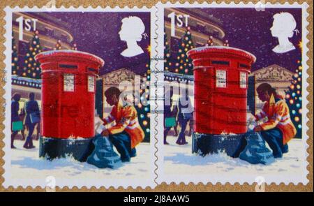 Photo de deux timbres-poste de Noël britanniques de classe 1st avec l'illustration d'une femme poste vidant une boîte postale 2018 Banque D'Images