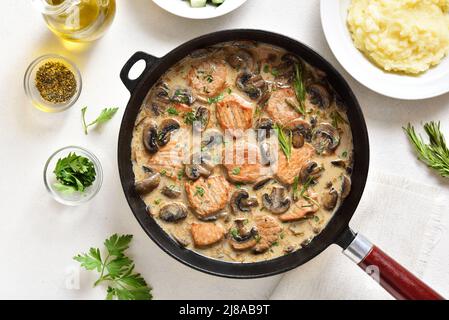 Médaillons de porc à la sauce aux champignons dans une casserole en fonte sur fond de pierre blanche.Vue de dessus, plan d'appartement Banque D'Images