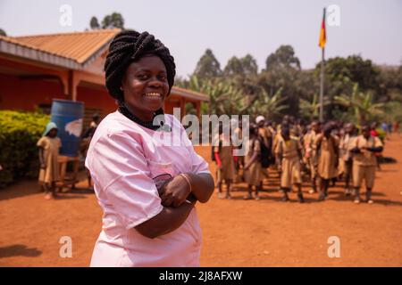 Professeur d'école africain suivant les élèves en chantant l'hymne national tout en levant le drapeau. Banque D'Images