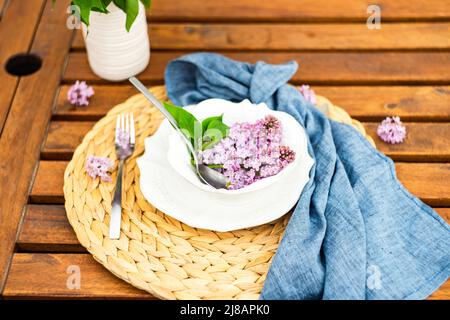 Décor printanier avec fleurs de lilas sur une table extérieure Banque D'Images