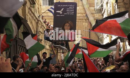 JÉRUSALEM, ISRAËL - 13 mai : les Palestiniens brandirent des drapeaux nationaux à l'extérieur de l'Église de notre-Dame de l'Annonciation lors de la cérémonie funéraire du journaliste palestinien Shireen Abu Akleh dans la vieille ville de 13 mai 2022, à Jérusalem, en Israël. La journaliste palestinienne américaine Shireen Abu Akleh a été tuée par balle alors qu'elle couvrait un raid militaire israélien dans la ville de Jénine, en Cisjordanie. Banque D'Images