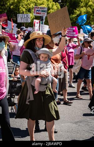 Photo d'une femme tenant un bébé et signe de protestation pendant la Roe interdictions de nos corps Mars et rassemblement organisé par Planned Parenthood. Banque D'Images