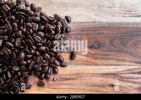Grains de café fraîchement torréfiés sur un comptoir en bois Banque D'Images