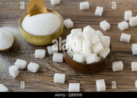 Cubes de sucre blanc dans un bol en bambou avec du sucre granulé sur une surface en bois Banque D'Images