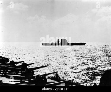 USS Lexington (CV-2) pendant l'action, vu de l'USS Yorktown (CV-5), 8 mai 1942. Un grand nombre d'avions sur le pont et le soleil bas indiquent que la photo a été prise tôt le matin, avant de lancer la grève contre la force aérienne japonaise. Yorktown a plusieurs SBD et F4Fs sur le pont avec des moteurs en marche, apparemment en préparation pour le décollage. Lexington, dont la silhouette a été modifiée par le retrait plus tôt de ses tourelles à canon de 8 pouces, a des avions garés avant et arrière, et peut être en train de forcer son pont en préparation pour lancer l'avion. Banque D'Images