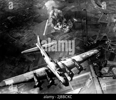 Un Boeing B-17F (« Virgin’s Delight », du 410th Bomb Squadron, 94th bombardement Group (Heavy), 8th Air Force,) survolant l’usine brûlante de Focke Wulf à Marenburg, en Allemagne. Ce raid a été un succès en ce que l'attentat de précision a signifié que l'usine a été fortement endommagée. Cependant, la distance à laquelle les avions devaient retourner au Royaume-Uni signifiait que la Luftwaffe avait suffisamment de temps pour se regrouper afin d'infliger de lourdes pertes aux bombardiers. Banque D'Images