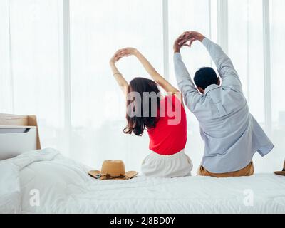 Couple de touristes, de joyeuses vacances. Vacances d'été. Portrait de la vue arrière de jeune asiatique homme et femme s'étirant avec la détente avec chapeau de plage sur le coup Banque D'Images