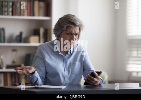 Une dame aînée frustrée et en colère s'est énervée avec le mauvais travail de l'application Banque D'Images